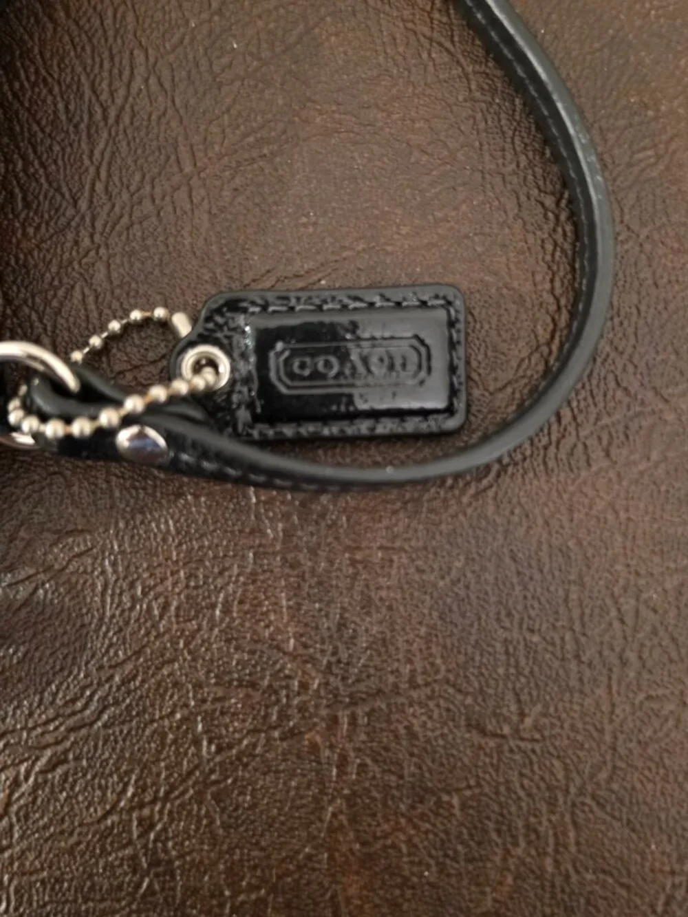 The Coach Signature Stitched Patent Leather Wristlet in black silver
